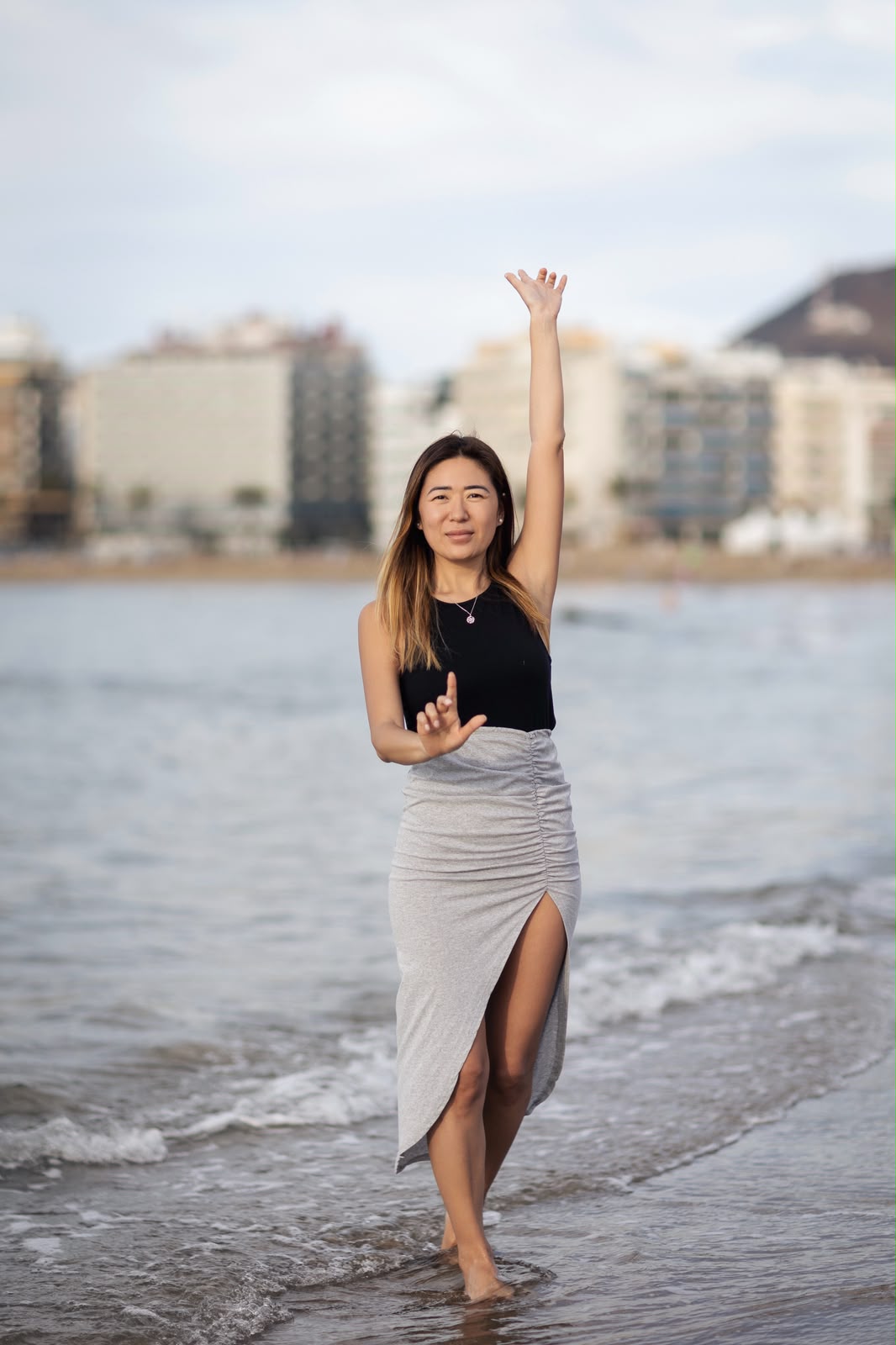 Blanca Zhang en la orilla del mar, con un brazo alzado
