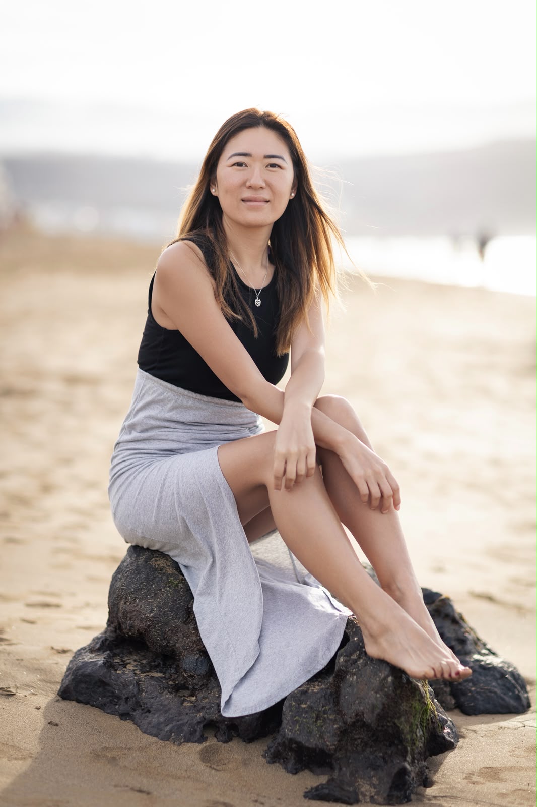 Blanca Zhang sentada sobre una roca en la playa